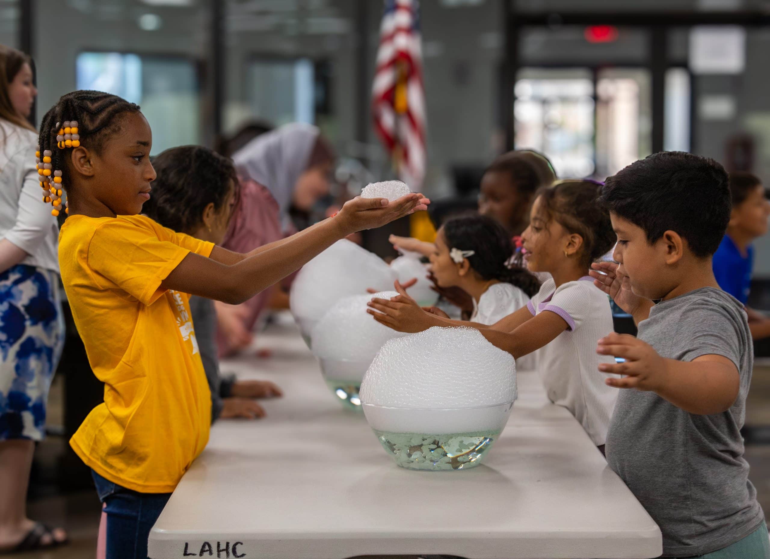 Children at an LAHC summer science session exploring bubbles at a hands-on activity table